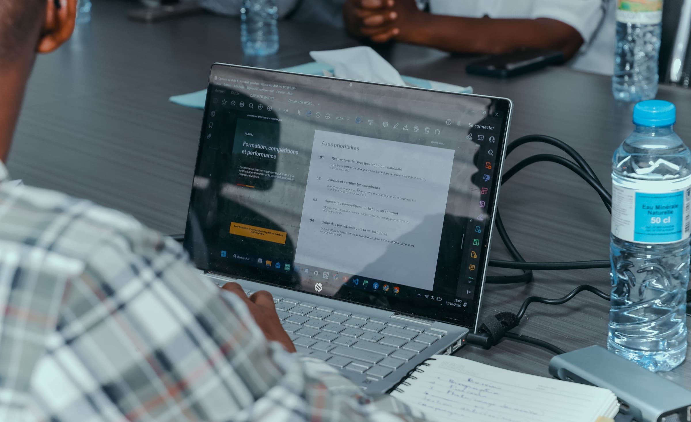 Réunion stratégique du 13 octobre 2026 : un ordinateur portable affiche les axes prioritaires du pilier « Formation, compétitions et performance »