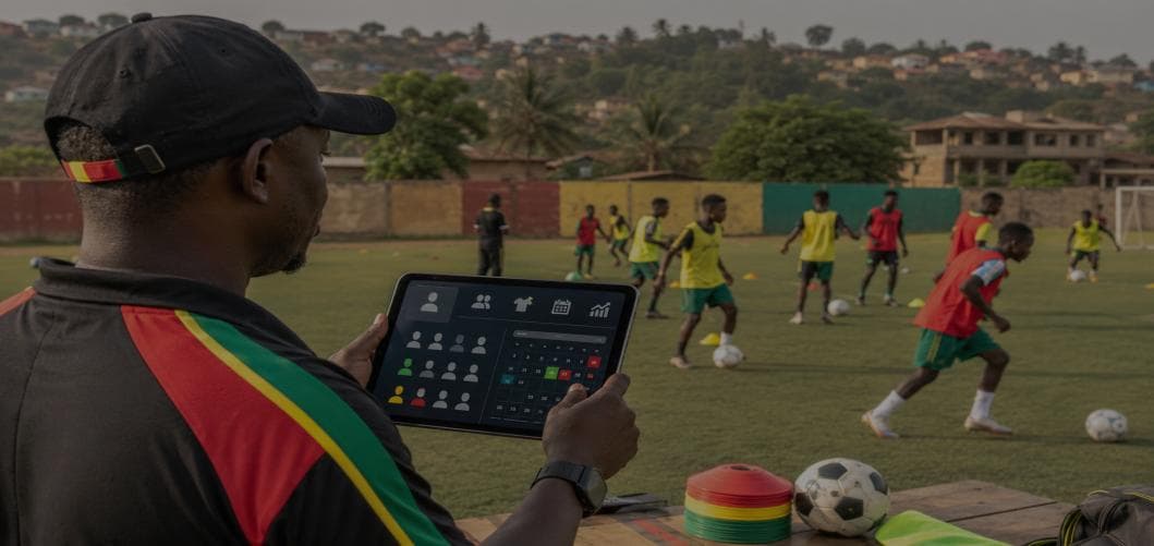 Un entraîneur consulte une tablette au bord du terrain pendant l’entraînement de jeunes joueurs